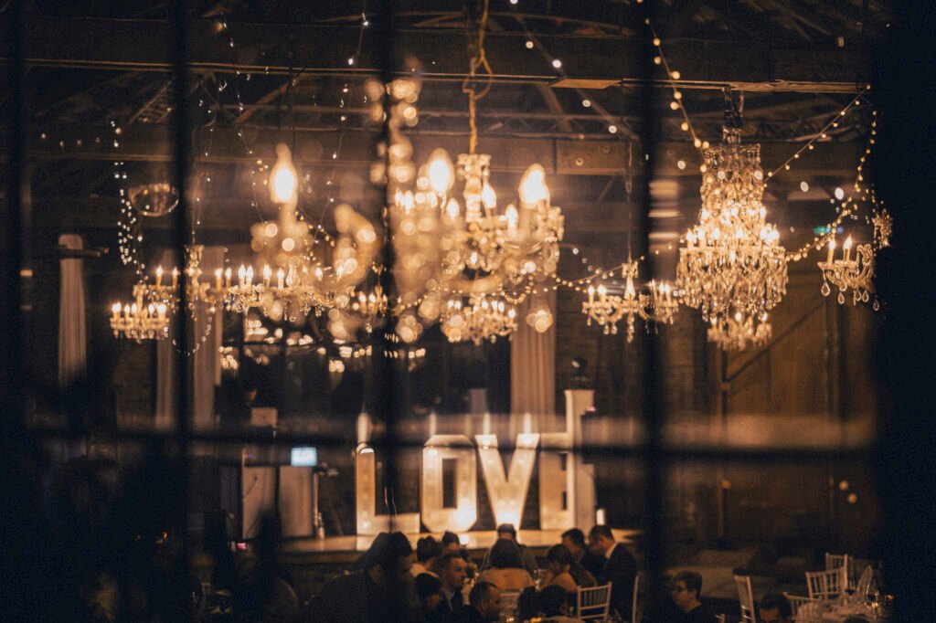 Atmospheric wedding celebration in an urban industrial venue in Cologne, Germany, featuring chandeliers and illuminated LOVE letters. Captured by a wedding photographer in Cologne.