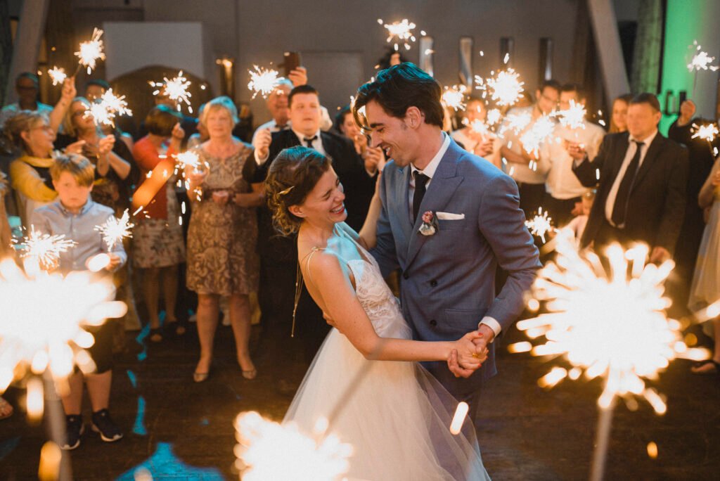 Laughing bride and groom dancing surrounded by sparklers at Landhaus Spatzenhof near Cologne, Germany – captured by an experienced wedding photographer
